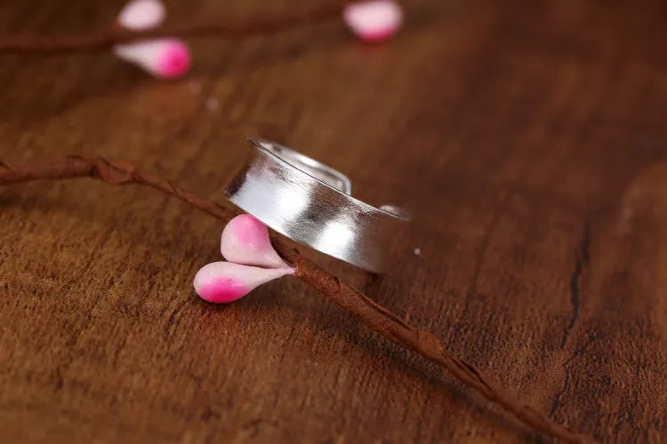 Geometric open ring with adjustable size in frosted sterling silver on a grey background.