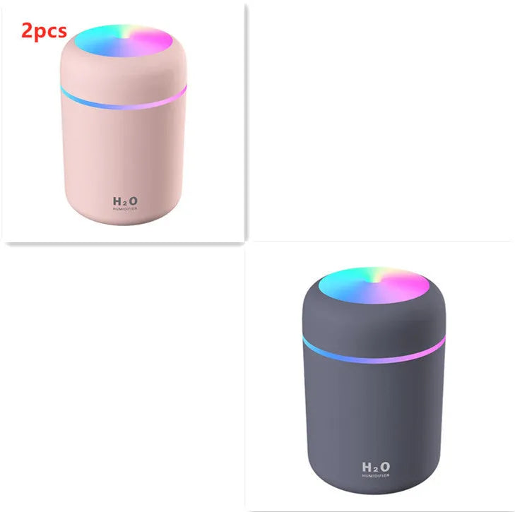 Pink USB desktop humidifier with coloured lights and water tank on a wooden desk