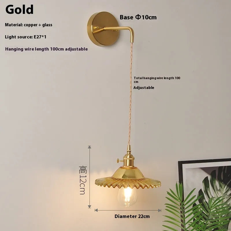 Brass lotus-shaped wall lamp with glass shade in choice of six colours on a plain wall.