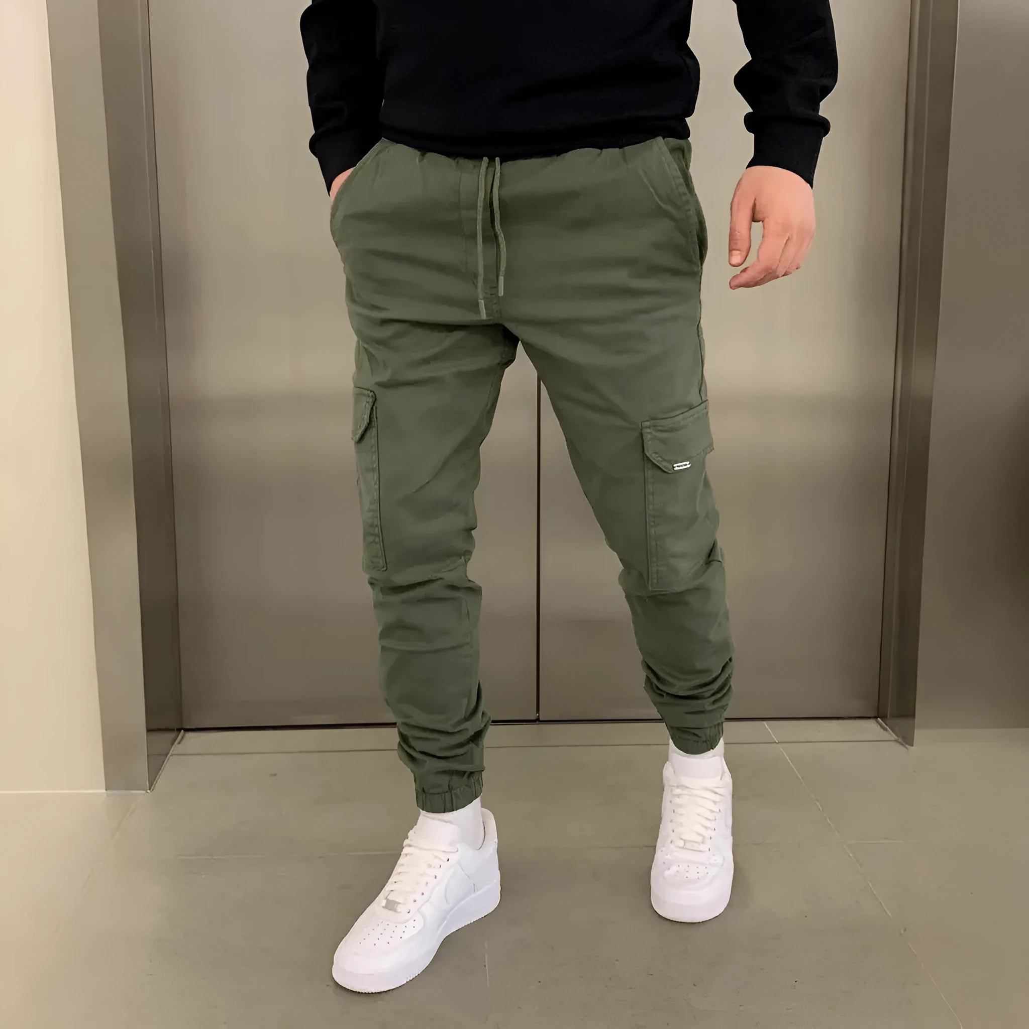 Man wearing loose light blue casual trousers with patch pockets and an elasticated waist.