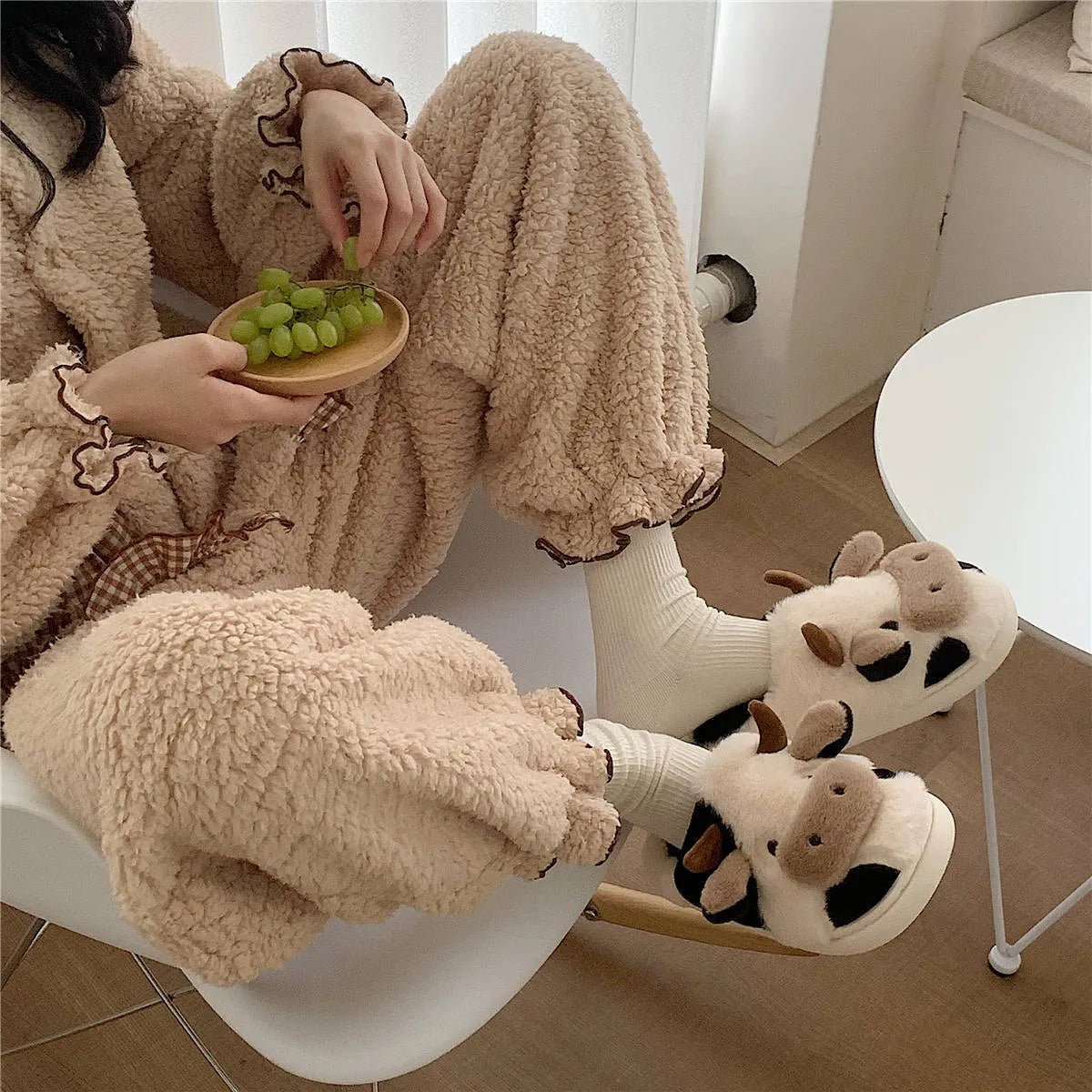 White cow-themed faux fur slippers with plush lining and textured non-slip soles.