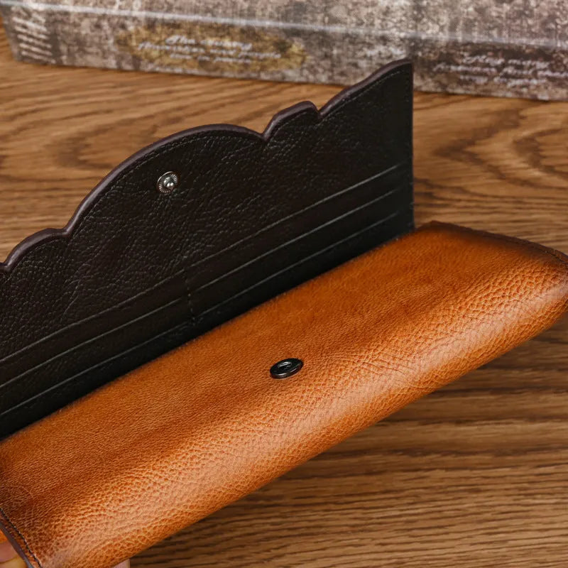Brown genuine leather tri-fold wallet with embossed floral pattern, shown open to display compartments.