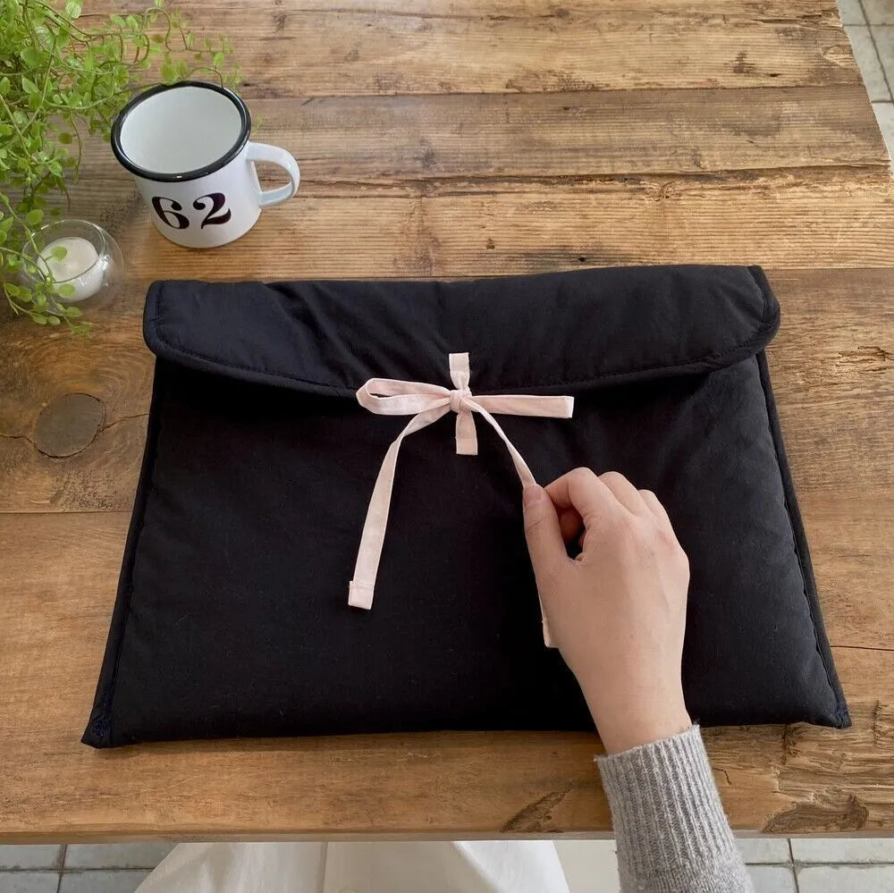 Women's black quilted laptop bag with ballet-style bow detail and striped pattern design