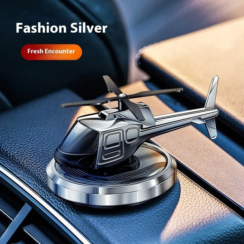 Silver metal helicopter car air freshener with rotating blades on dashboard