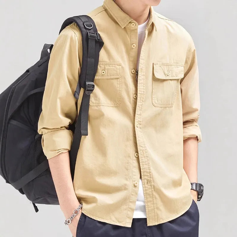 Man wearing a loose grey cardigan-style button-up shirt with long sleeves.