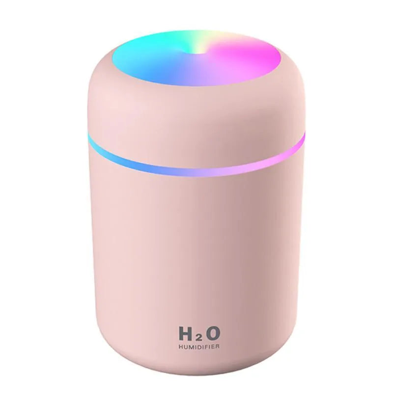 Pink USB desktop humidifier with coloured lights and water tank on a wooden desk