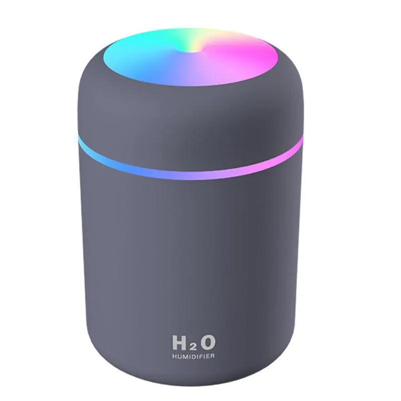 Pink USB desktop humidifier with coloured lights and water tank on a wooden desk