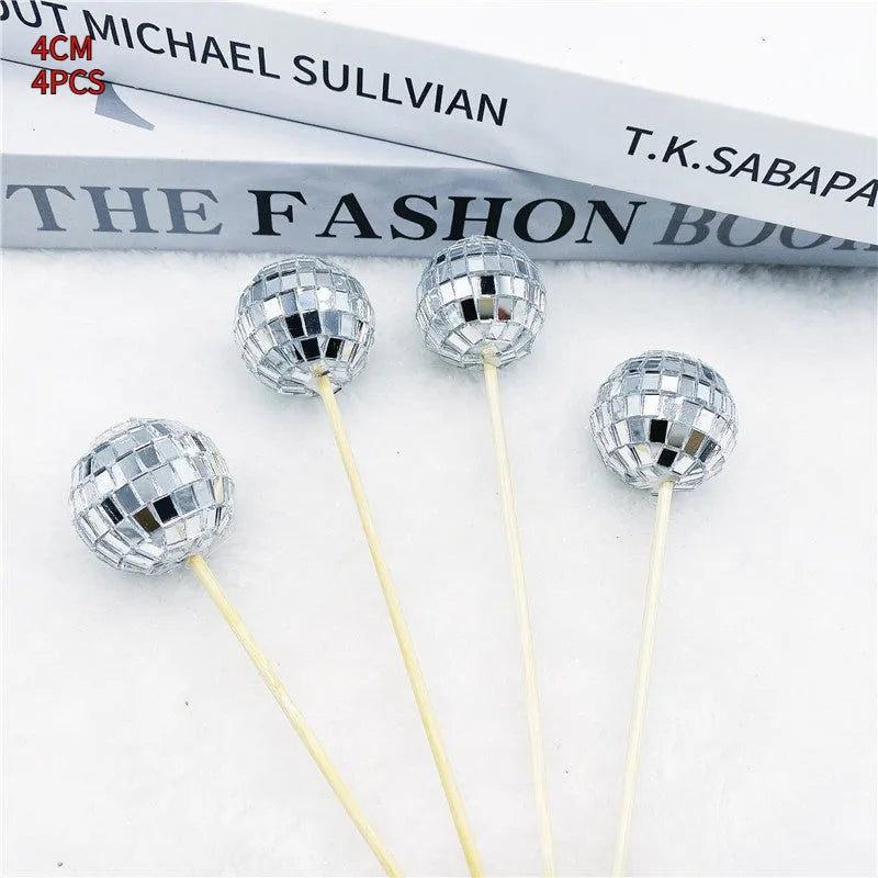 Glass mirror ball cake decoration on a wooden stick, showing reflective surface.