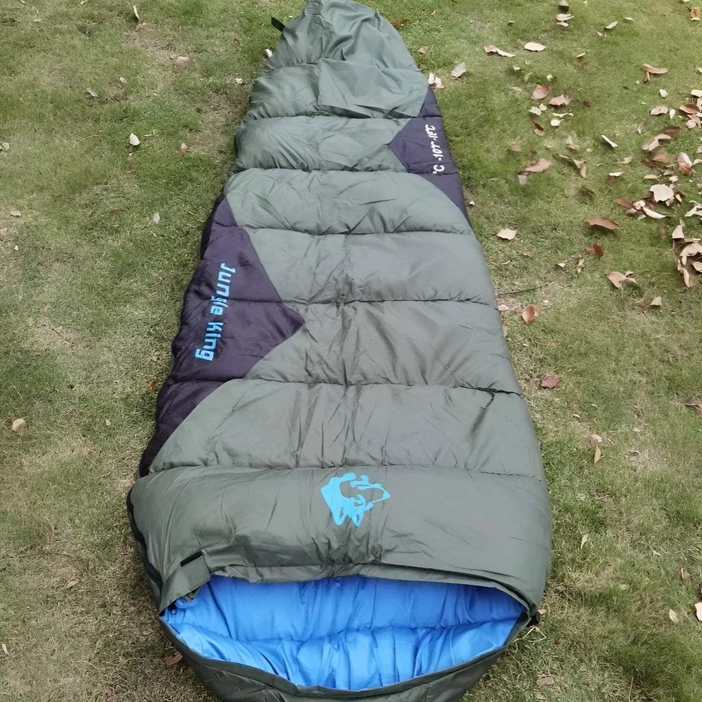 Outdoor cotton sleeping bag in army green with its compression storage bag laid alongside.