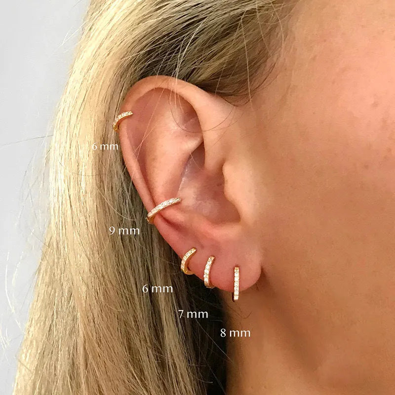 Perforated circle stud earrings with zircon detail in gold, rose gold, and silver colours on a white background.