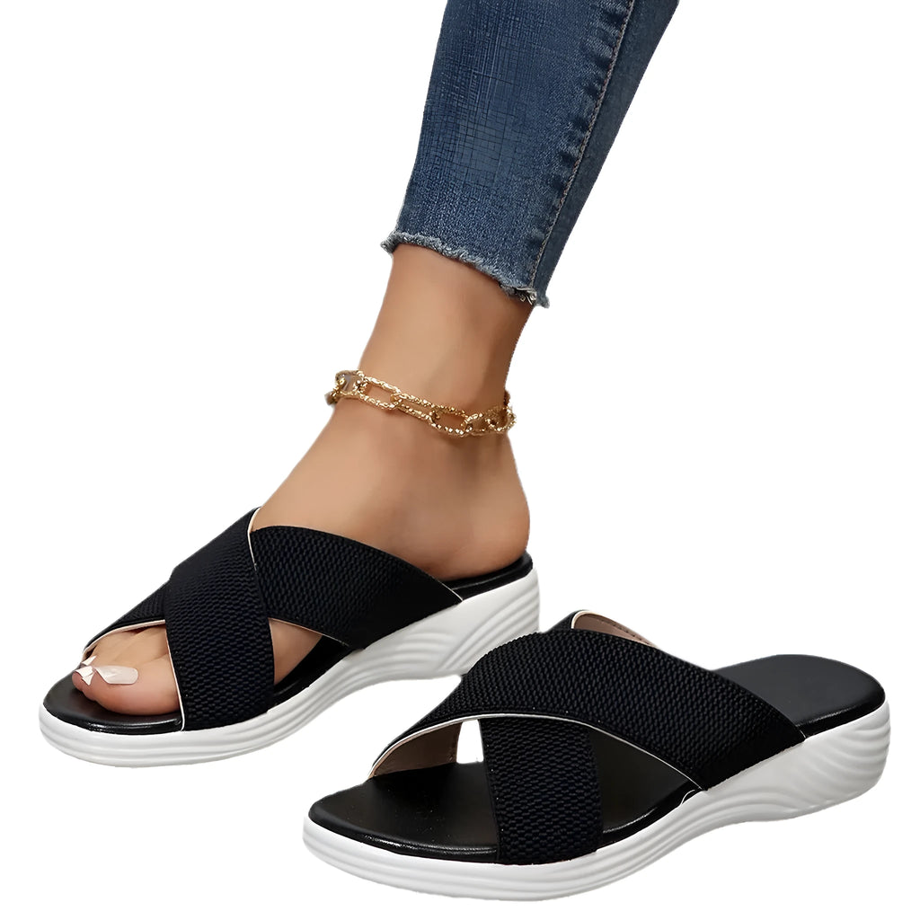 Women's black wedge slippers with a cross strap and peep toe on a thick rubber sole.