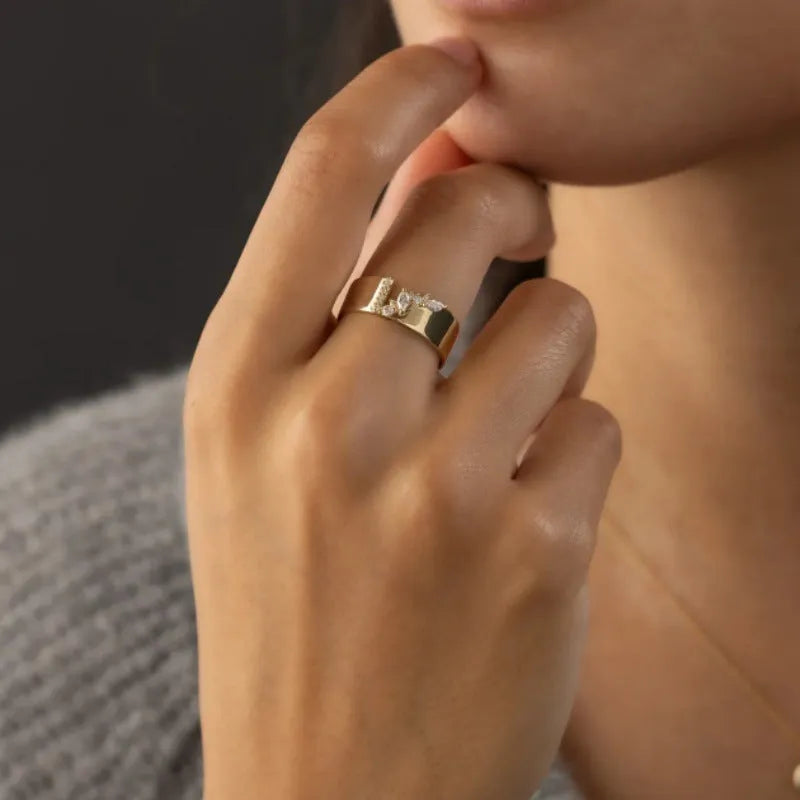 Gold-coloured copper ring with a shining zircon stone on a model's hand.