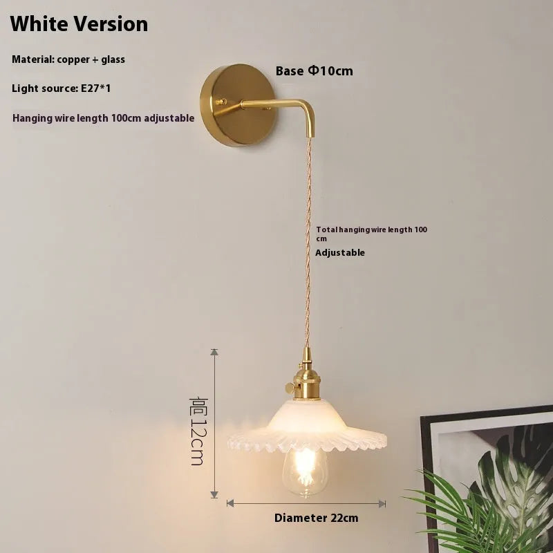 Brass lotus-shaped wall lamp with glass shade in choice of six colours on a plain wall.