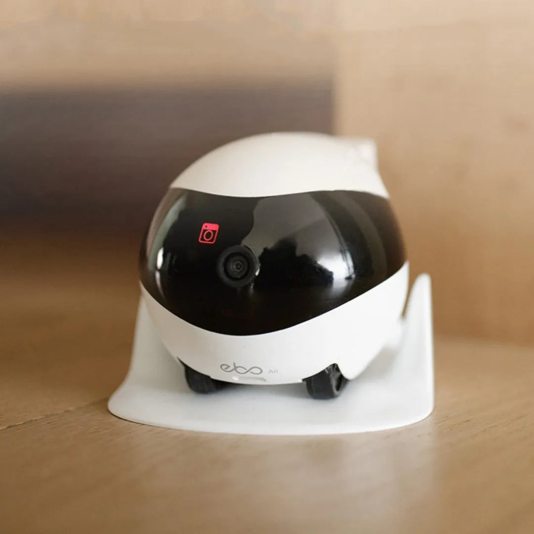 White mobile surveillance robot camera with wheels next to its automatic charging docking station