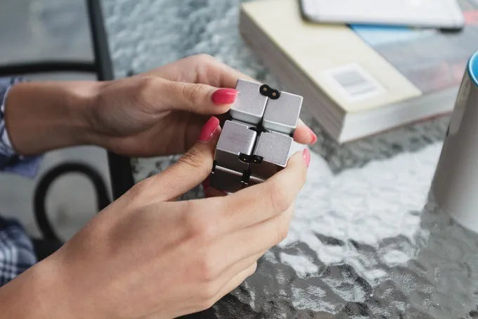 Silver zinc alloy infinity cube fidget toy with rotating segments shown on a flat surface