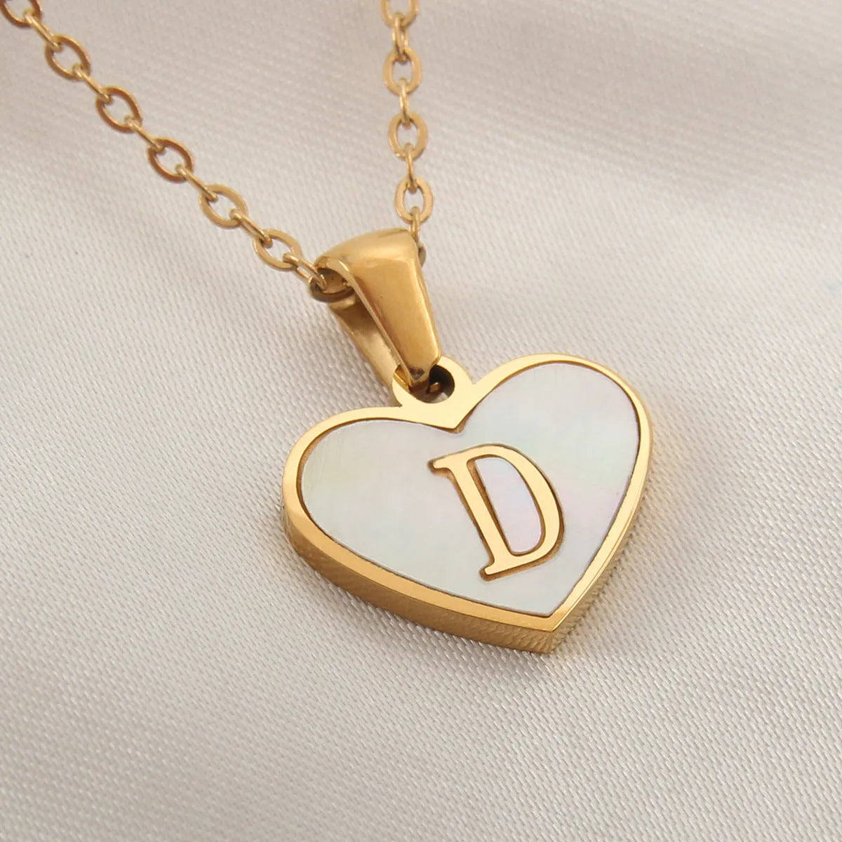 Gold plated heart-shaped white shell pendant personalised initial necklace on a stainless steel chain.