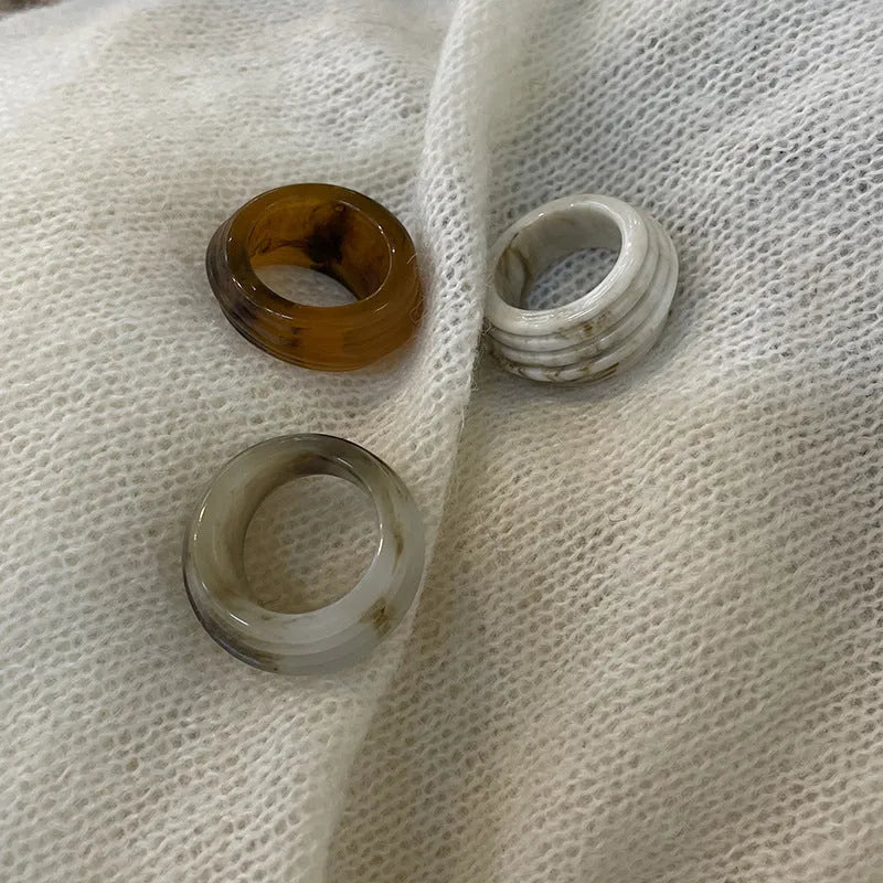 Geometric irregular resin wide ring in brown and white colours on a plain background.