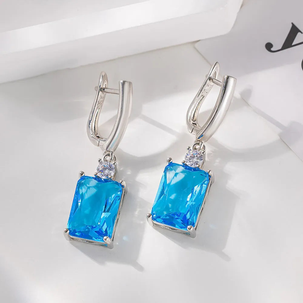 A pair of square-shaped gold-coloured geometric earrings on a white background.