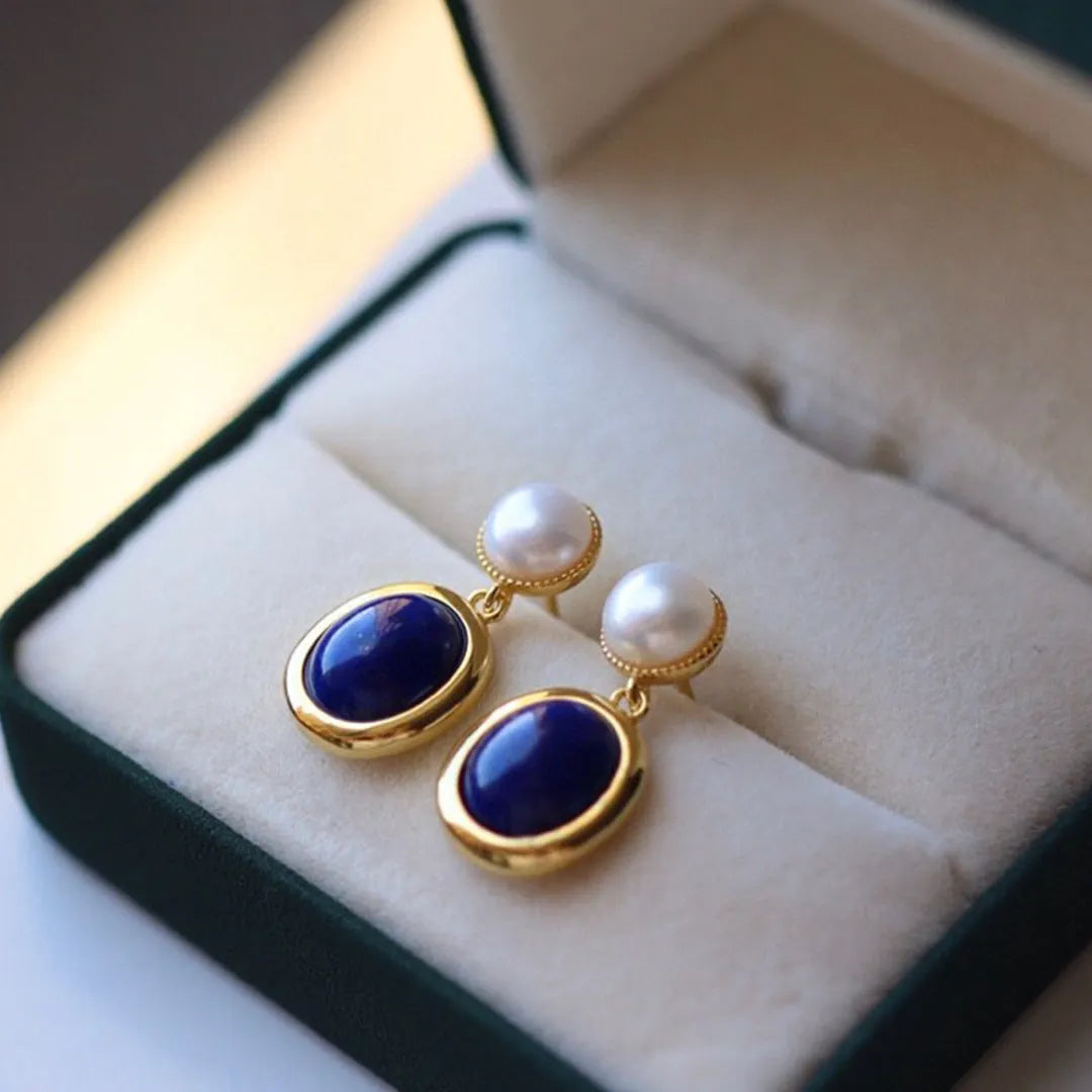 A pair of simple stud earrings with a blue lapis lazuli pearl set in a sterling silver setting.