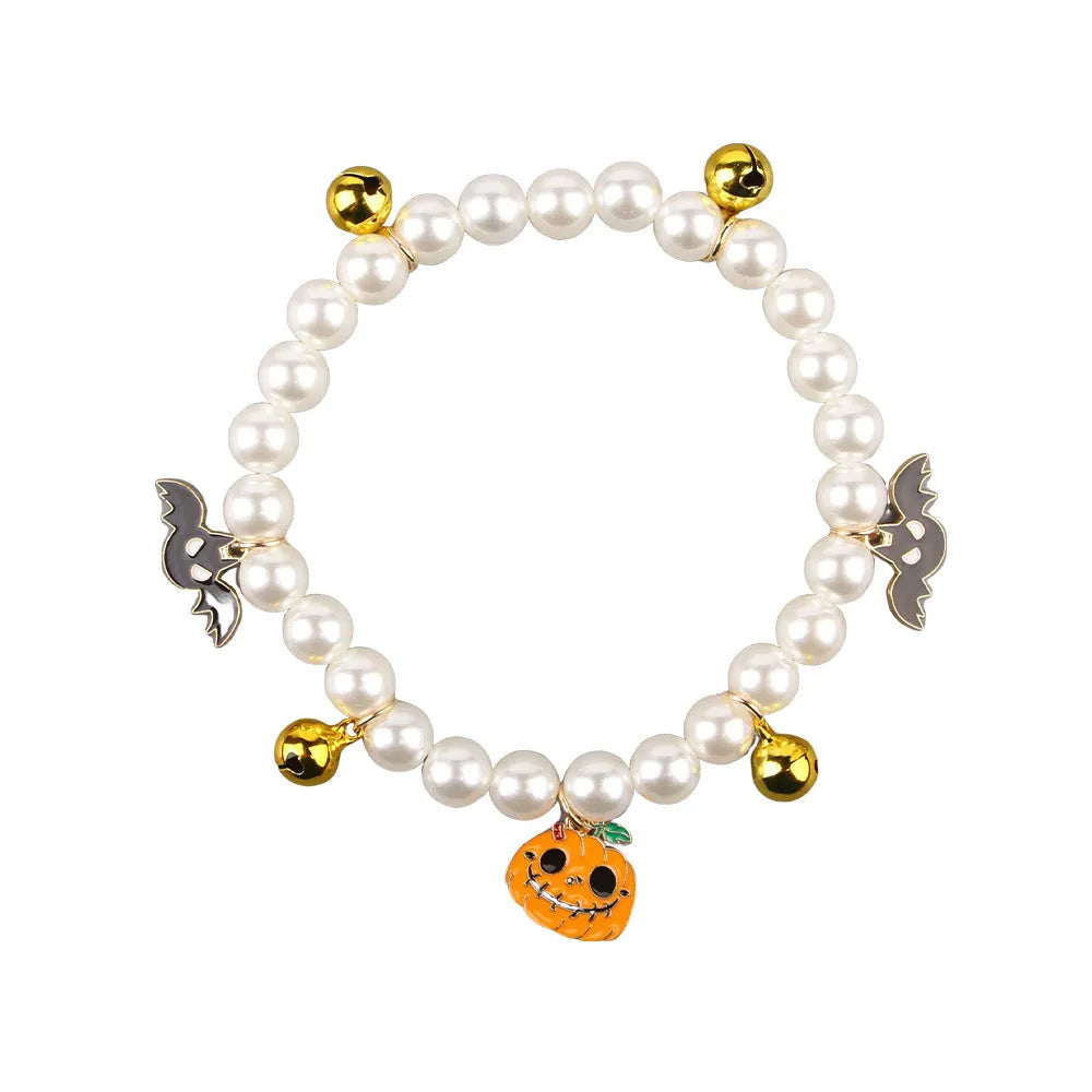 Close-up of a simulated pearl cat collar with a detailed Halloween pumpkin charm, showing the purple ghost design variant.