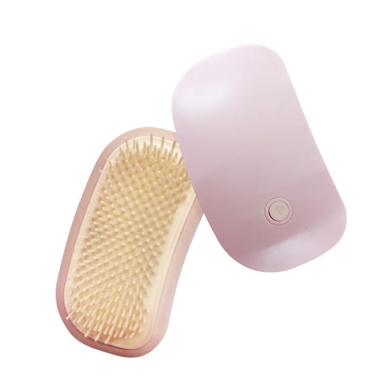 Pink handheld electric vibration pet grooming brush with soft TPE teeth on a white background.