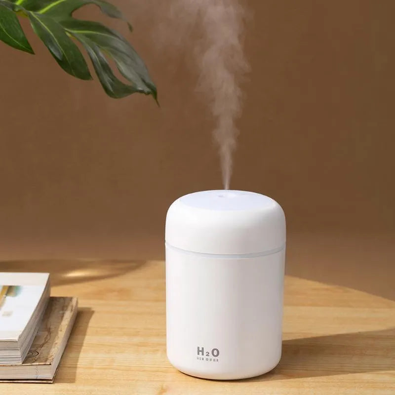 Pink USB desktop humidifier with coloured lights and water tank on a wooden desk