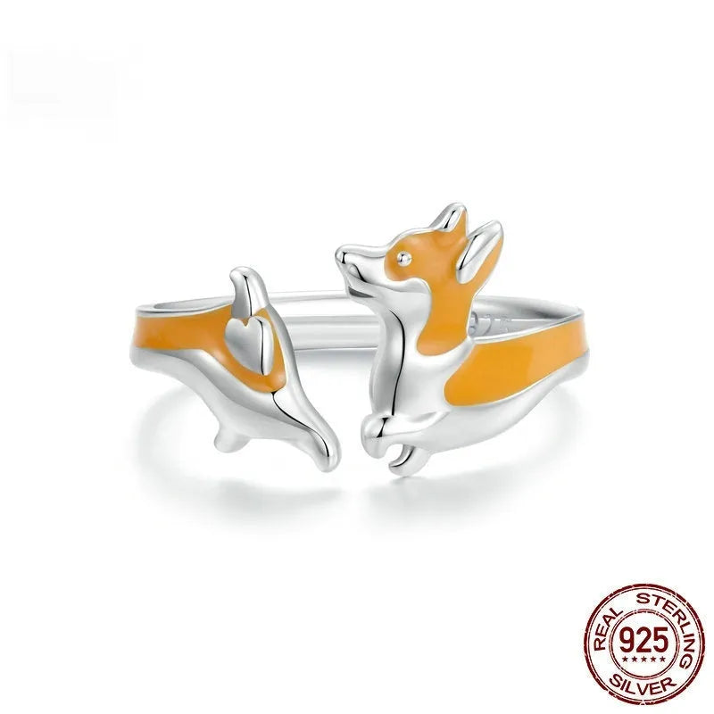 Silver corgi pet cartoon ring with electroplated colour on a model's finger.