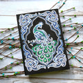 Black A5 notebook with a peacock design made from shaped and bright diamond painting drills.