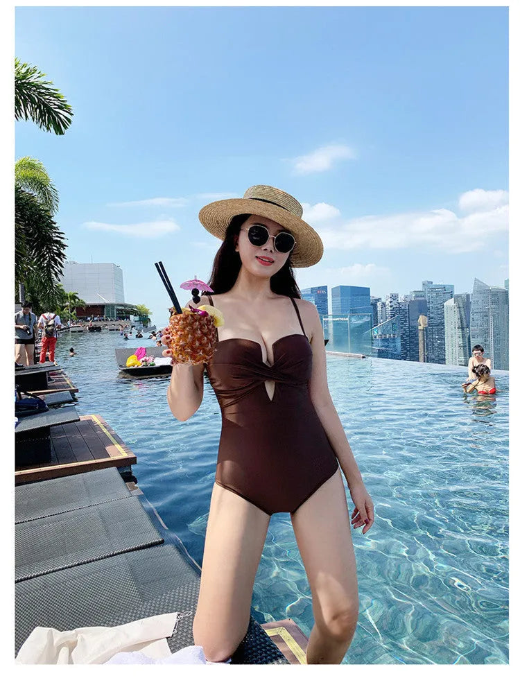 Women's solid colour one-piece swimsuit with spaghetti straps and push-up design in white, pink, or brown.