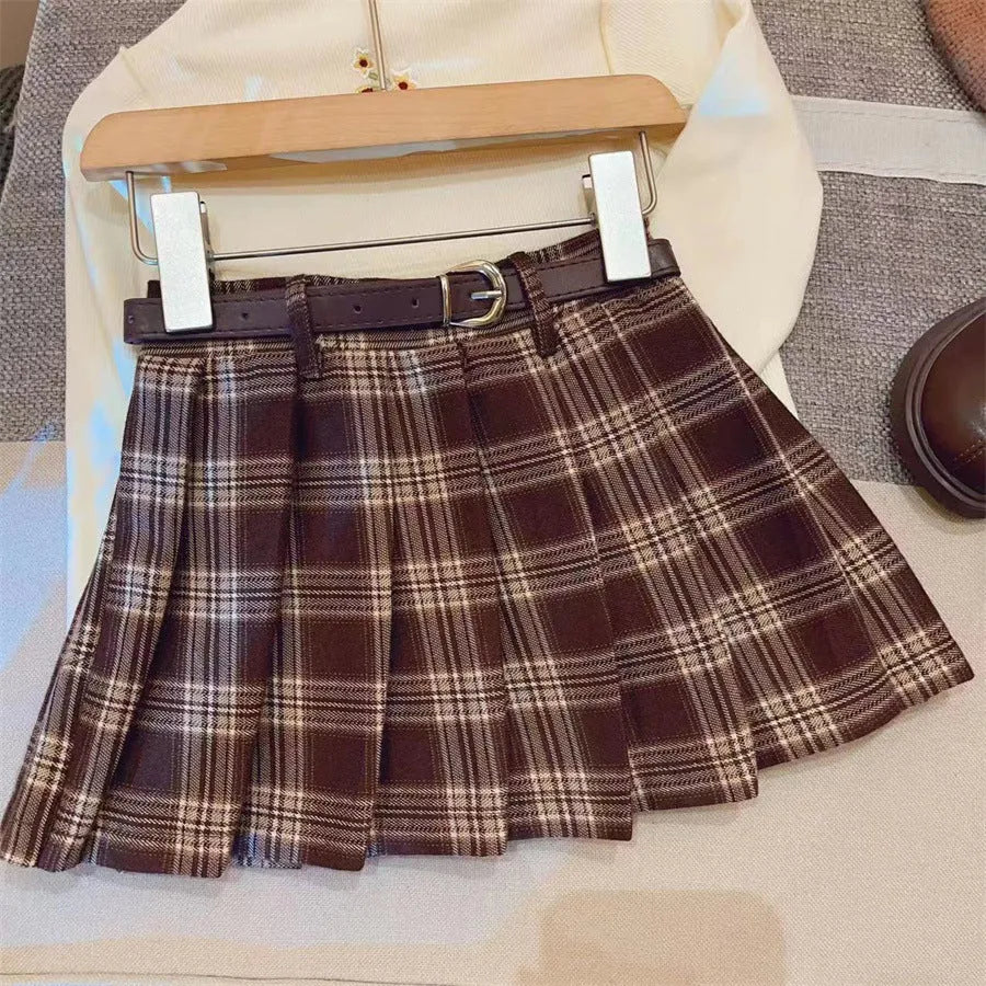 Girls' red and black plaid pleated A-line skirt on a hanger, showing cotton lining.