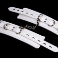 White PU sponge bondage set showing handcuffs, footcuffs, and a neck scarf laid out.