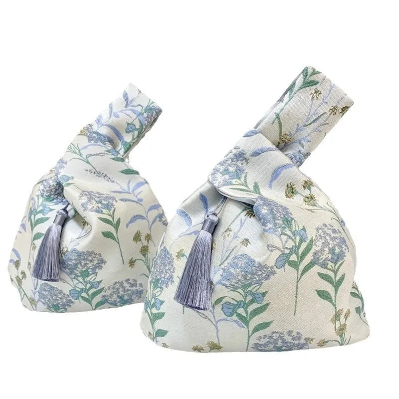 Chinese style gold silk jacquard hand-held cloth gift bag with flower accent in champagne colour on white background
