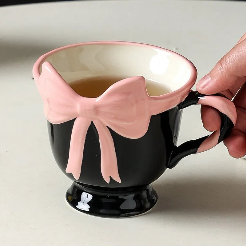 Ceramic mug with a heart and bow design in black pink and white powder colour options.