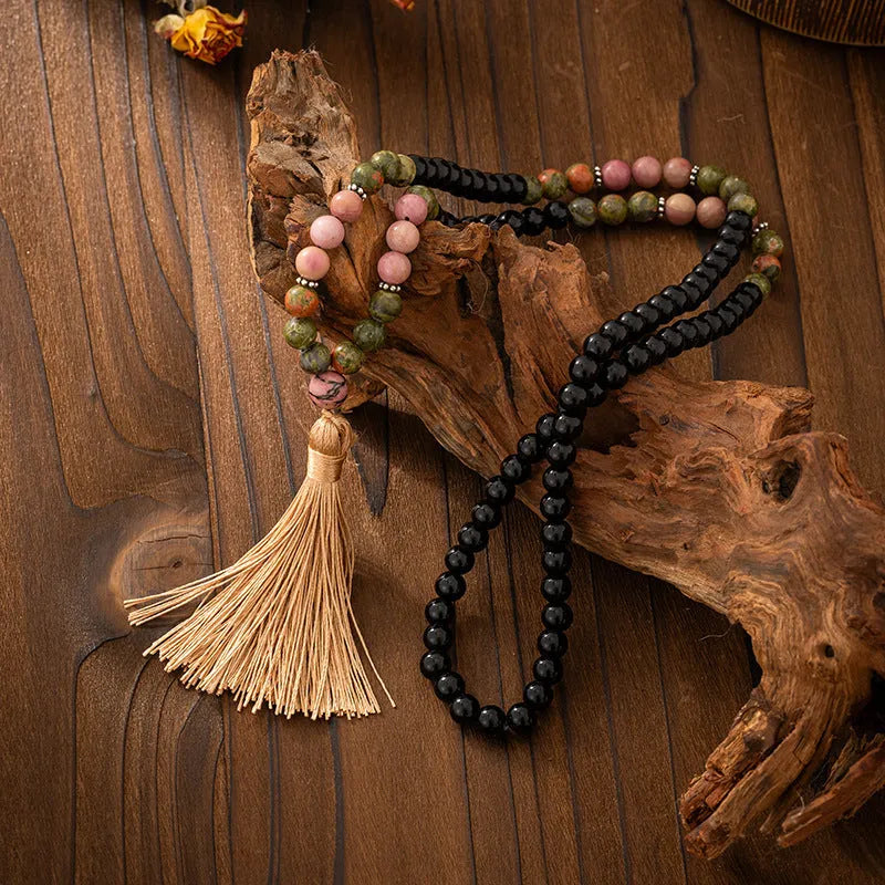 Long natural stone beaded sweater chain necklace and matching bracelet in bohemian style on a grey background.