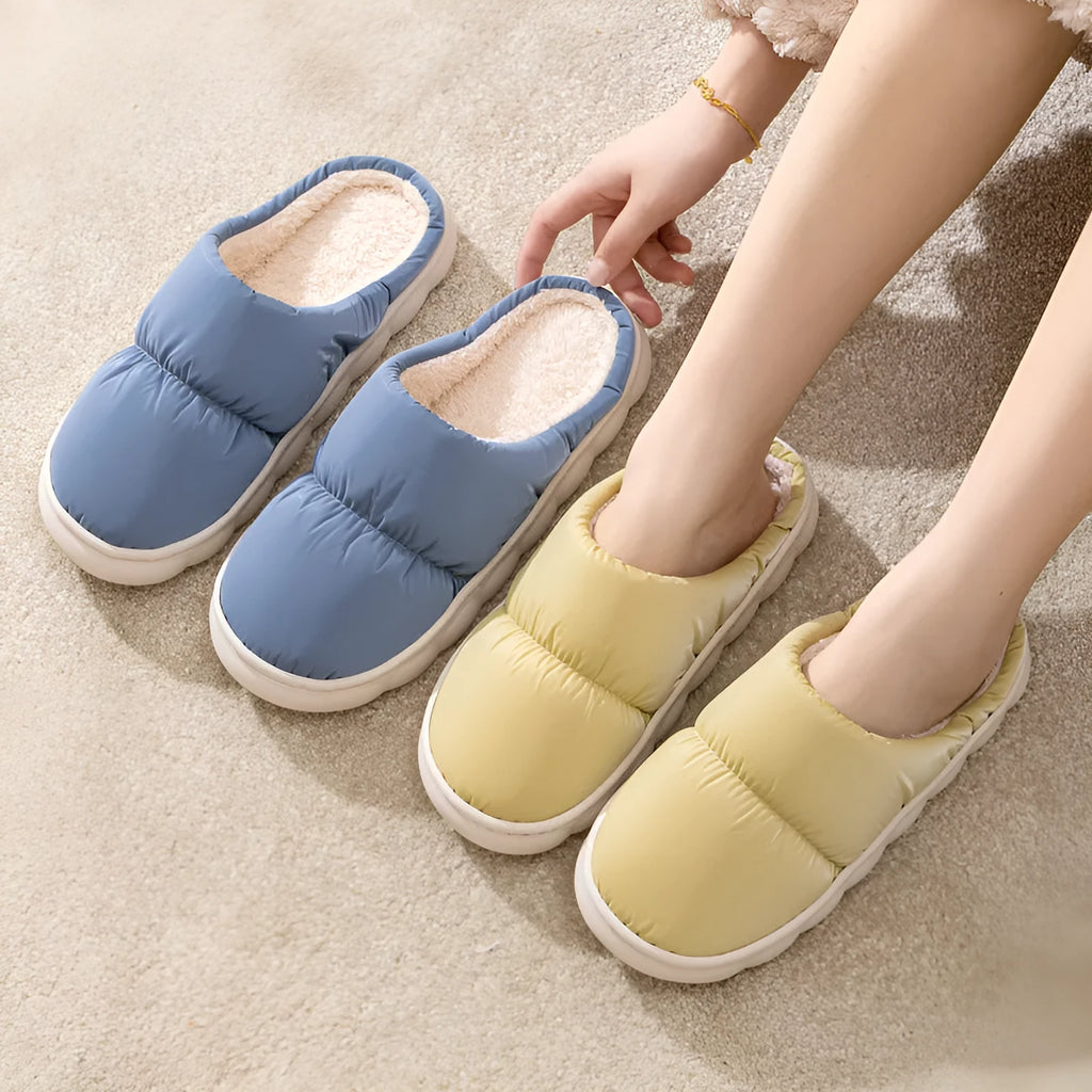 Blue down cotton indoor slippers with thick rubber sole and plush lining, shown on a wooden floor.