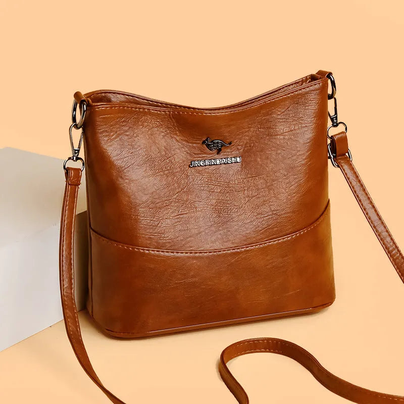 Women's soft leather bucket shoulder bag in black, shown with minimalist design and sewing line detail.