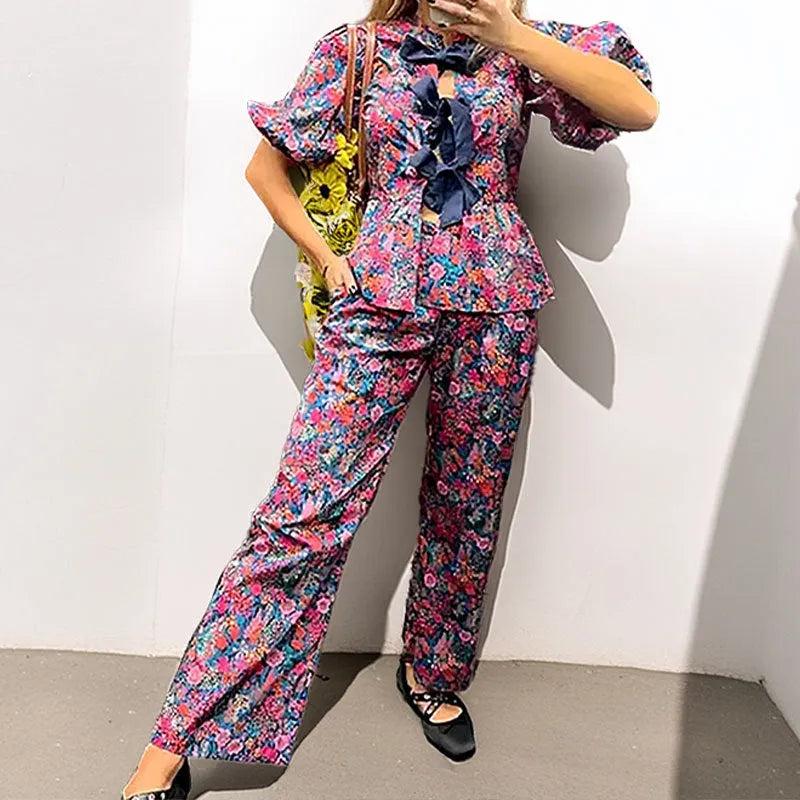 Women's floral print tie-neck trouser suit with puff sleeves, shown in the picture colour.