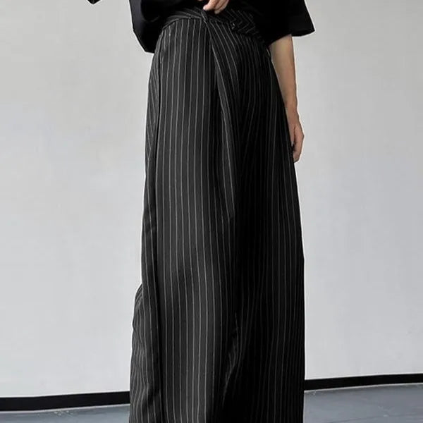 Men's black vertical striped pleated casual trousers showing elastic waistband and tapered leg