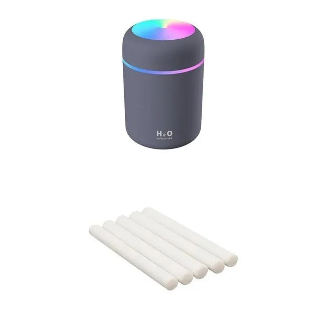 Pink USB desktop humidifier with coloured lights and water tank on a wooden desk
