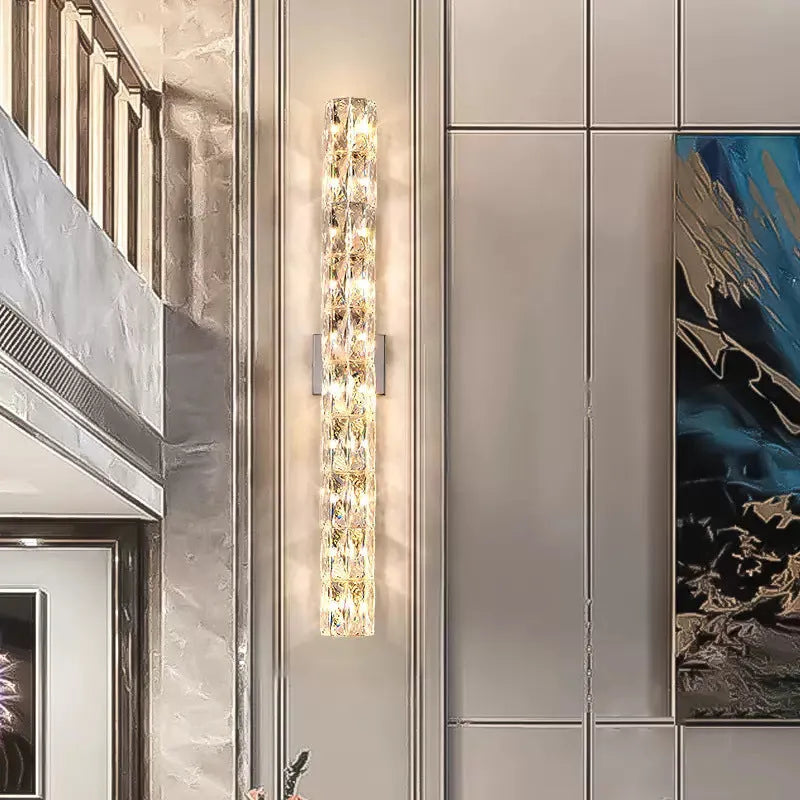 Slim crystal and stainless steel wall lamp with LED light on a wall.