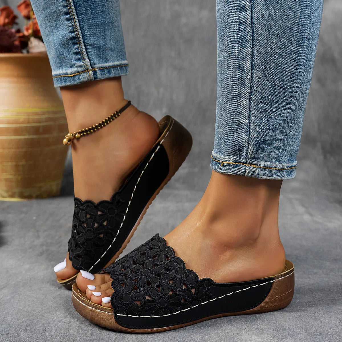 Women's black beach slipper with flower cutouts, a fish mouth toe, and a low wedge heel on a rubber sole.