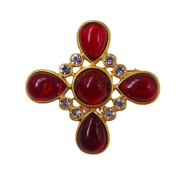 Close-up of a medieval-style baroque cross brooch with crystal decoration on a metal base.