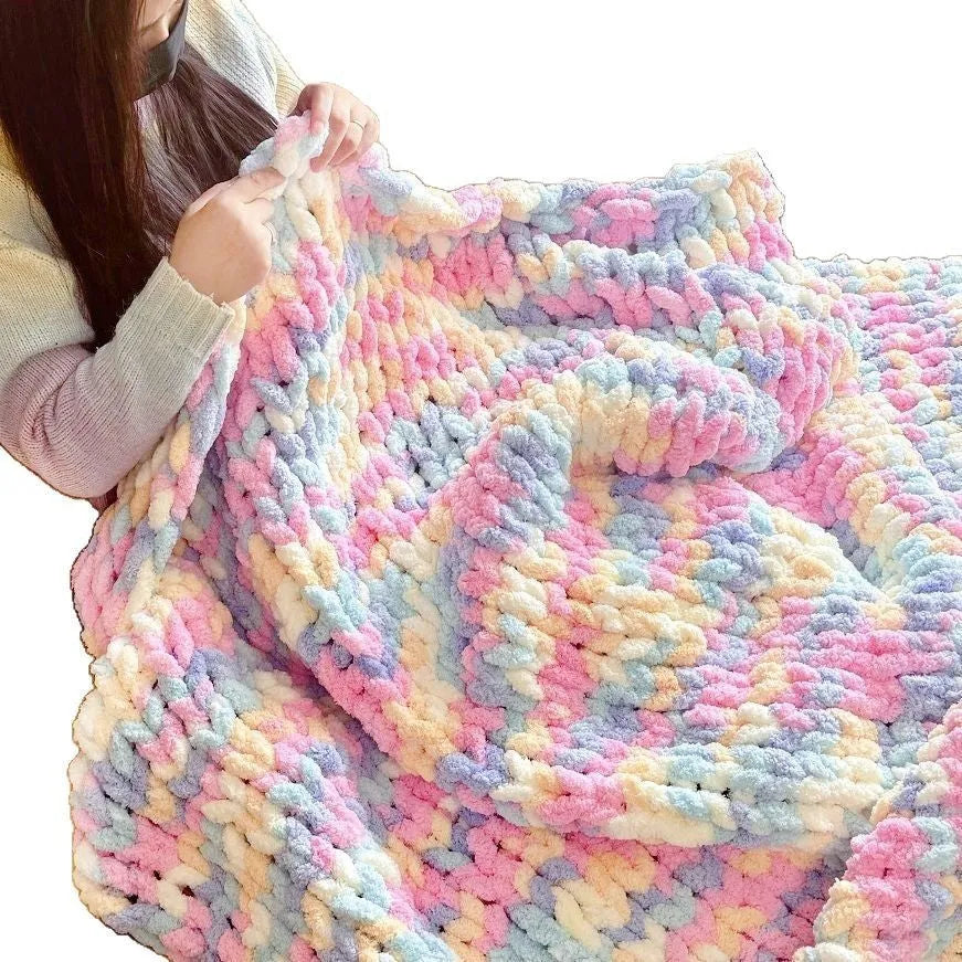 Coarse yarn chenille knitted blanket with braided gravity trim in a modern colour on a bed.
