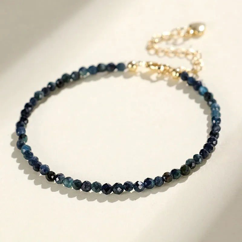 Close-up of a women's blue tourmaline gemstone beaded bracelet with 3mm beads and spacer design.