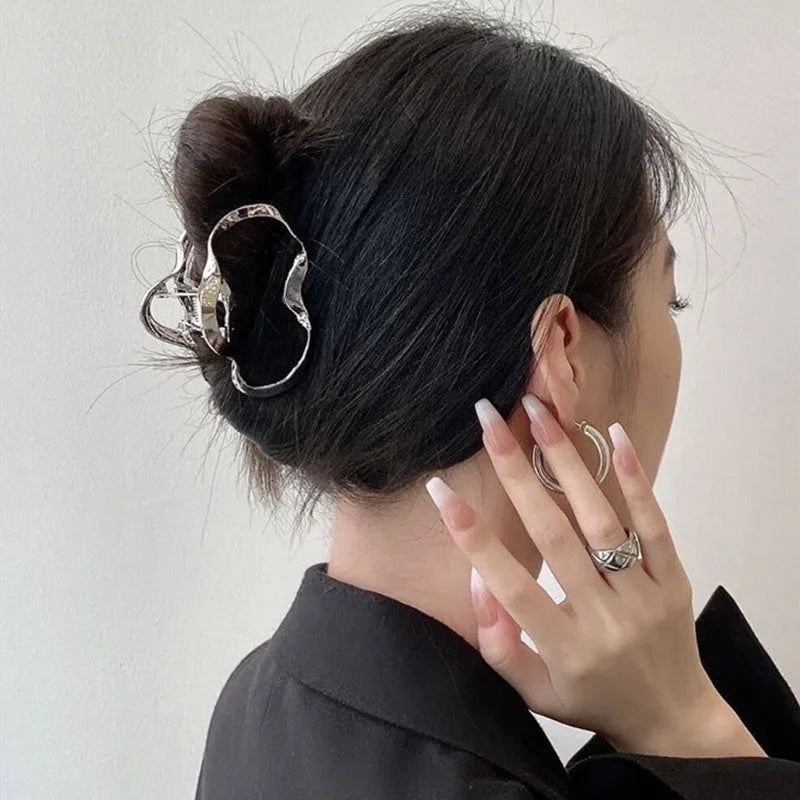Assortment of silver metal hair claw barrettes with various designs including bows, pearls, and geometric shapes.
