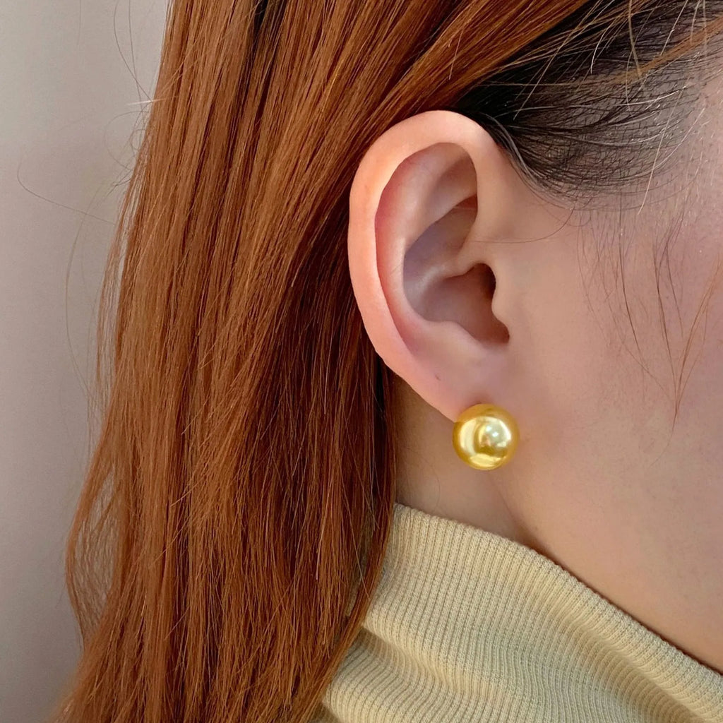 A pair of large geometric pearl stud earrings with an eight-point star detail on silver settings.
