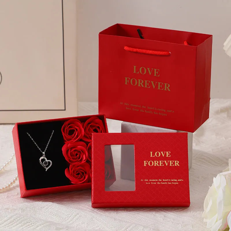 Red Korean style soap flower gift set with six roses in a box next to a matching handbag.