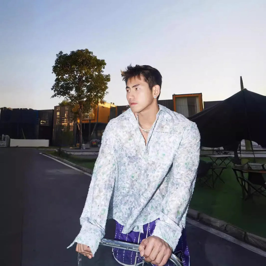 Man wearing a blue loose-fit long sleeve shirt with an embossed three-dimensional floral pattern.