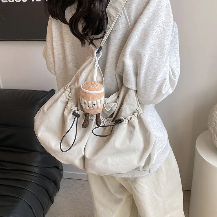 Ultra-light pleated green crossbody cloth bag lying flat, showing its split pocket and foldable design.