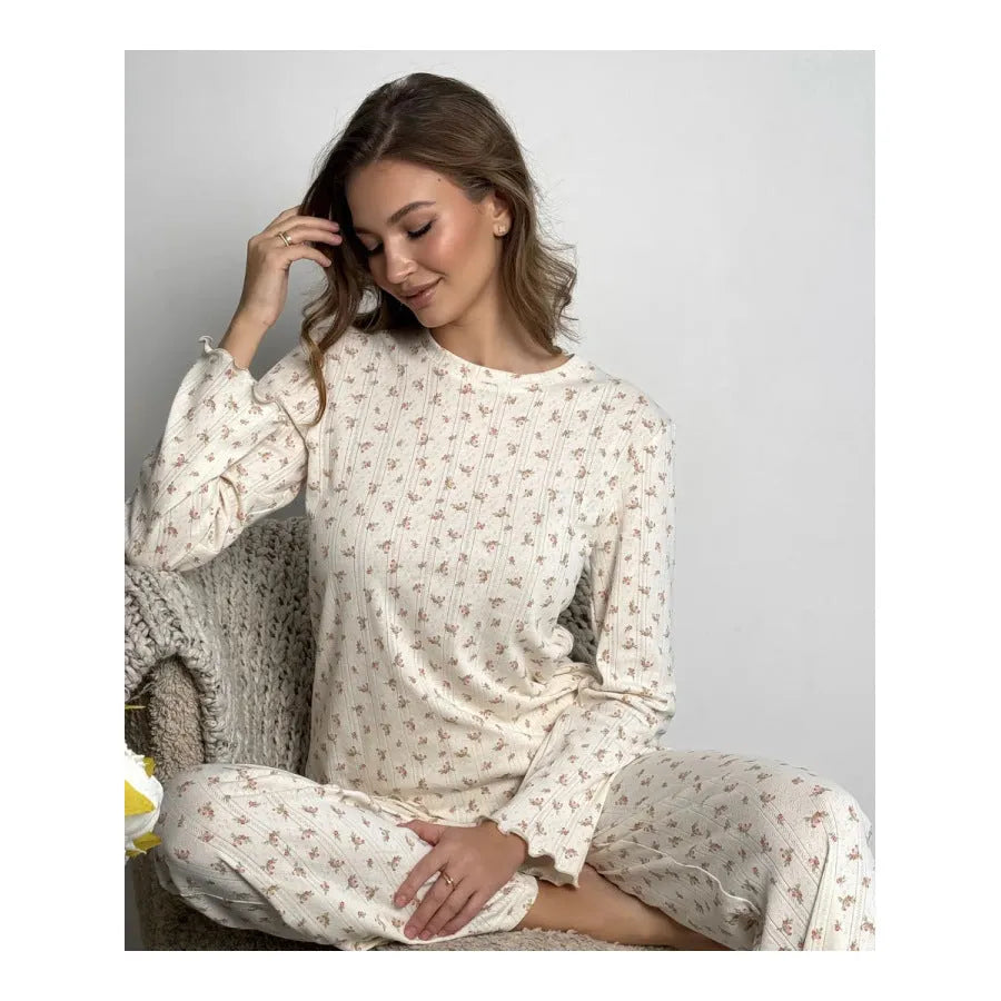 White floral print women's two-piece suit with bell sleeve top and wide leg trousers laid flat.